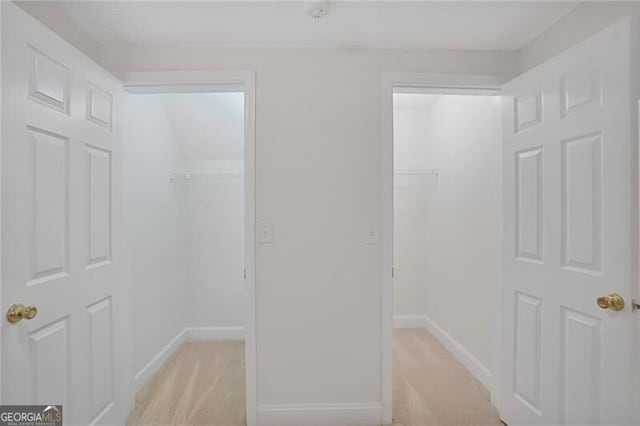 hall with baseboards and light colored carpet