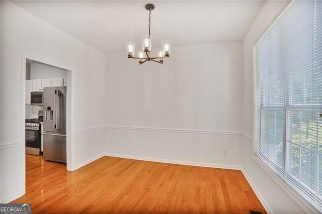 unfurnished dining area with visible vents, baseboards, light wood-style floors, and a chandelier