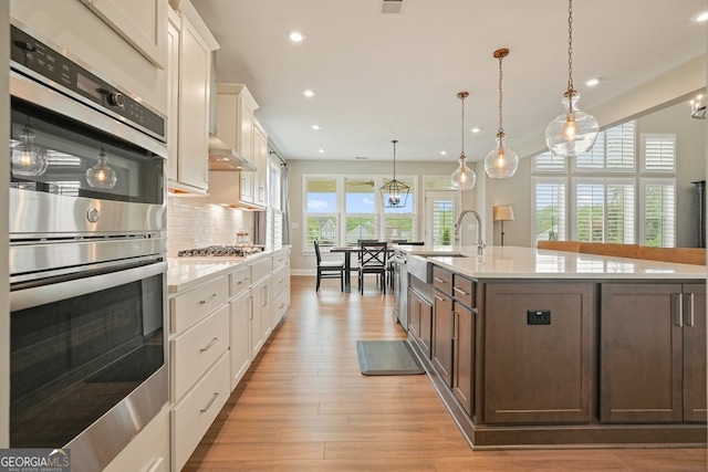 2127 Harmony Dr, Canton, GA 30115 - kitchen with double oven, light countertops, recessed lighting, a kitchen island with sink, and dark brown cabinets