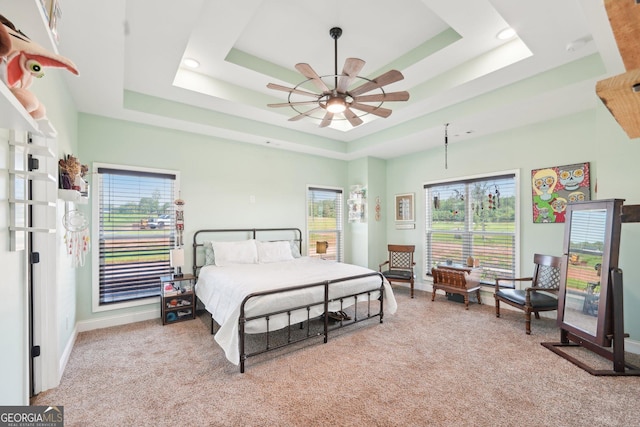 bedroom featuring recessed lighting, a tray ceiling, light colored carpet, and baseboards