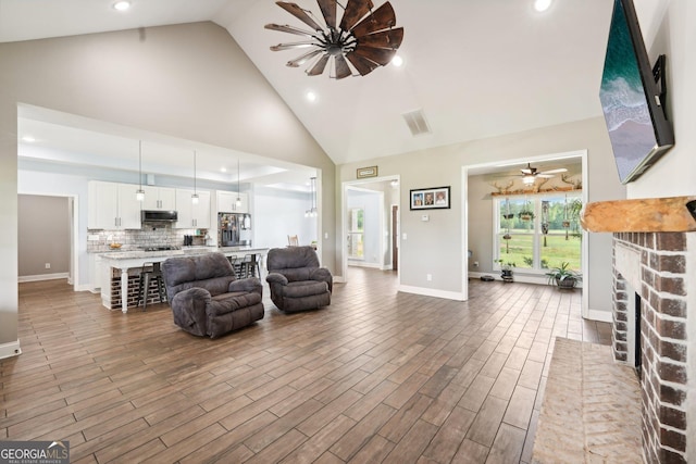 living room with a brick fireplace, recessed lighting, high vaulted ceiling, and visible vents