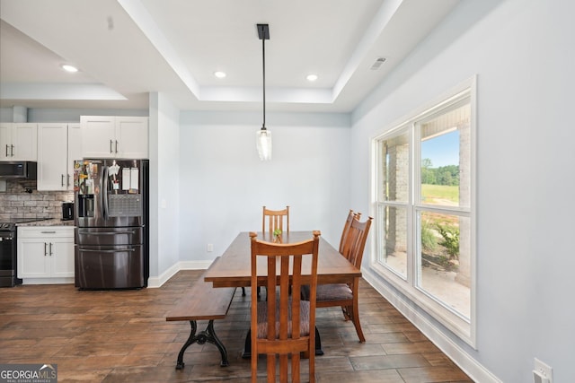 dining space featuring recessed lighting, a tray ceiling, dark wood-style floors, and baseboards