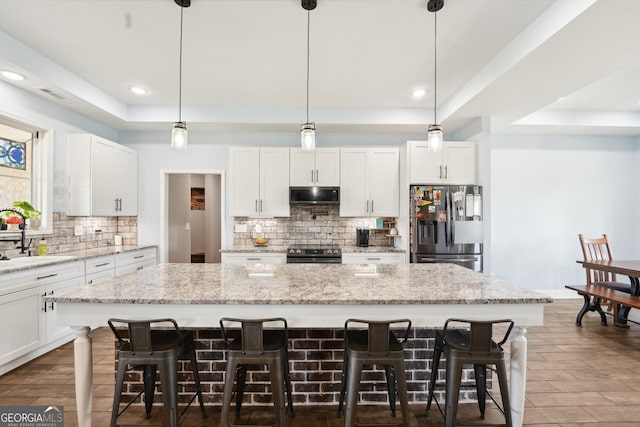 kitchen featuring decorative backsplash, appliances with stainless steel finishes, a sink, a raised ceiling, and recessed lighting