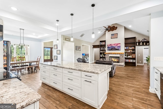 kitchen with a brick fireplace, wood finished floors, white cabinets, and ceiling fan