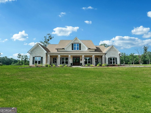 view of front of property with brick siding, a front lawn, and covered porch