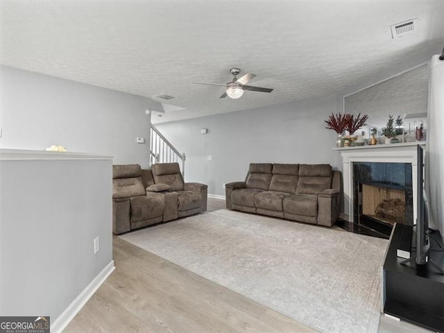 4643 Grand Central Pkwy, Decatur, GA 30035 - living area with wood finished floors, ceiling fan, a tiled fireplace, a textured ceiling, and baseboards