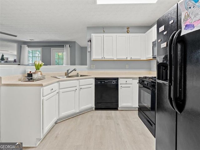 4643 Grand Central Pkwy, Decatur, GA 30035 - kitchen featuring black appliances, a sink, light wood-style floors, white cabinets, and a textured ceiling