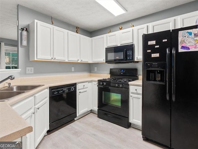 4643 Grand Central Pkwy, Decatur, GA 30035 - kitchen with black appliances, a sink, light wood-style floors, white cabinets, and light countertops