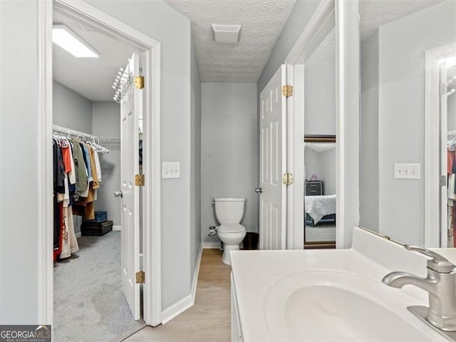 4643 Grand Central Pkwy, Decatur, GA 30035 - bathroom featuring toilet, a textured ceiling, vanity, baseboards, and a walk in closet