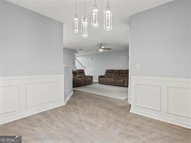 4643 Grand Central Pkwy, Decatur, GA 30035 - unfurnished living room with a wainscoted wall, wood finished floors, stairway, a decorative wall, and a ceiling fan