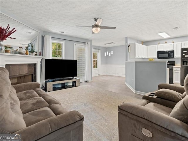 4643 Grand Central Pkwy, Decatur, GA 30035 - living area with light wood-style flooring, a textured ceiling, ceiling fan, wainscoting, and a fireplace