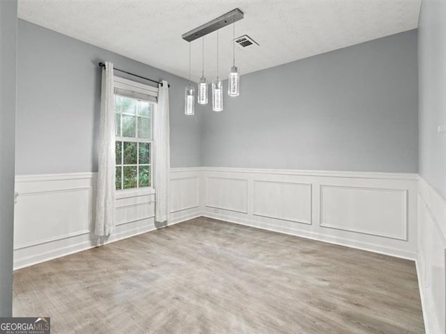 4643 Grand Central Pkwy, Decatur, GA 30035 - unfurnished dining area featuring wainscoting, wood finished floors, a decorative wall, and a textured ceiling