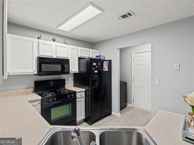 4643 Grand Central Pkwy, Decatur, GA 30035 - kitchen with black appliances, white cabinetry, light countertops, light wood finished floors, and a textured ceiling