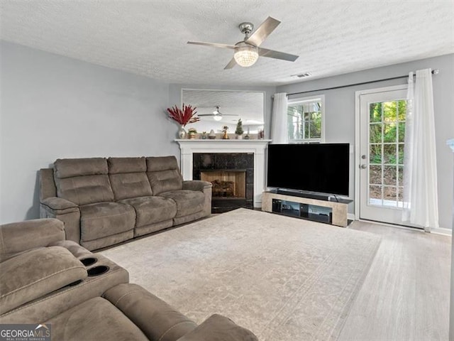 4643 Grand Central Pkwy, Decatur, GA 30035 - living area with a textured ceiling, a ceiling fan, a fireplace, and wood finished floors