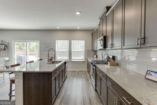 kitchen featuring backsplash, a sink, baseboards, a kitchen bar, and appliances with stainless steel finishes