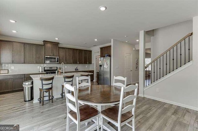 5876 Hackberry Ln, Braselton, GA 30517 - dining space featuring light wood-type flooring, recessed lighting, stairway, and baseboards