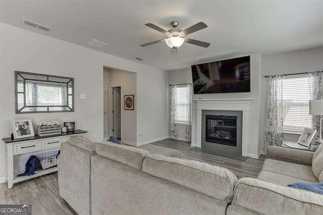 living room with light wood finished floors, baseboards, a ceiling fan, and visible vents