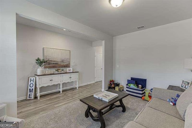 living area featuring visible vents, baseboards, and wood finished floors