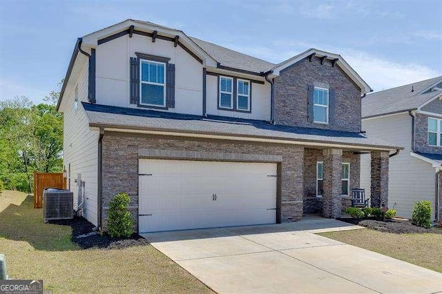 craftsman house with driveway, stone siding, an attached garage, cooling unit, and a front yard