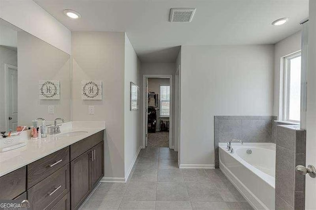 bathroom featuring a bath, tile patterned floors, baseboards, visible vents, and vanity