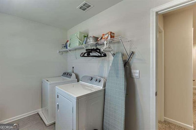 washroom with washing machine and clothes dryer, baseboards, visible vents, and laundry area