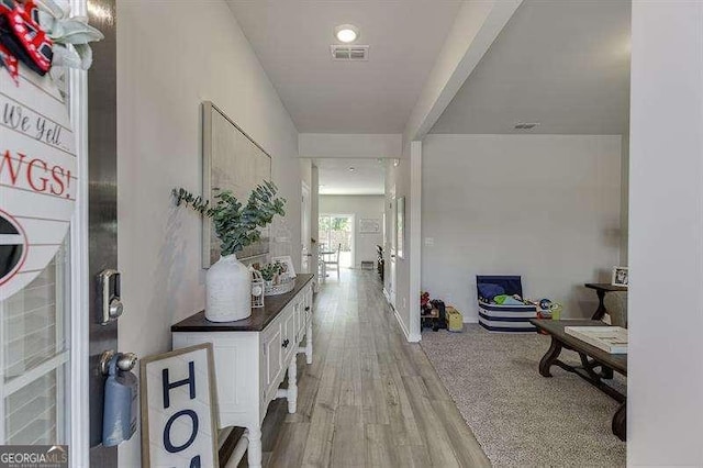 hallway with light wood-style floors and visible vents