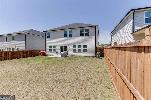 back of house with a fenced backyard and a yard