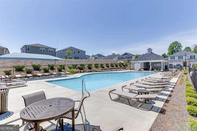 community pool with fence, a residential view, and a patio