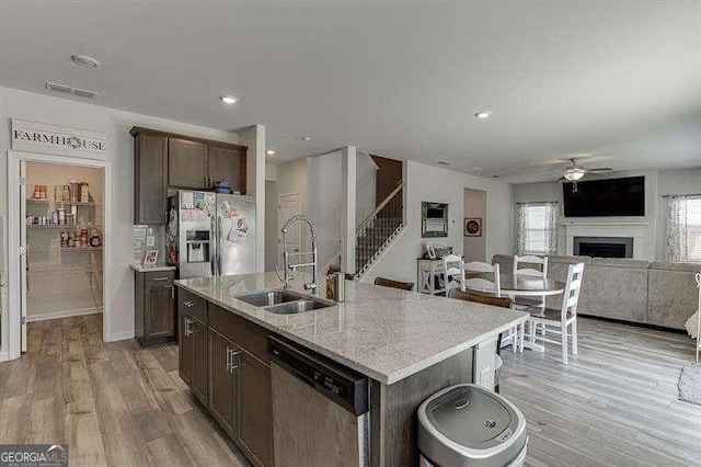 kitchen featuring a sink, light wood-style flooring, ceiling fan, a fireplace, and appliances with stainless steel finishes