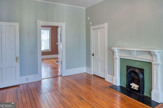 unfurnished living room featuring a fireplace with flush hearth, hardwood / wood-style flooring, and baseboards