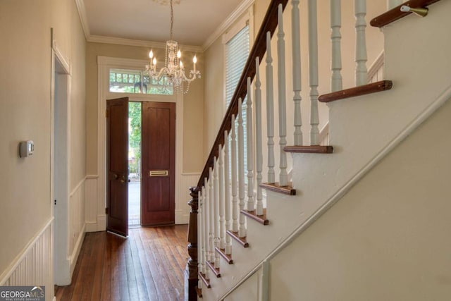 foyer with wainscoting, a chandelier, stairs, crown molding, and hardwood / wood-style floors
