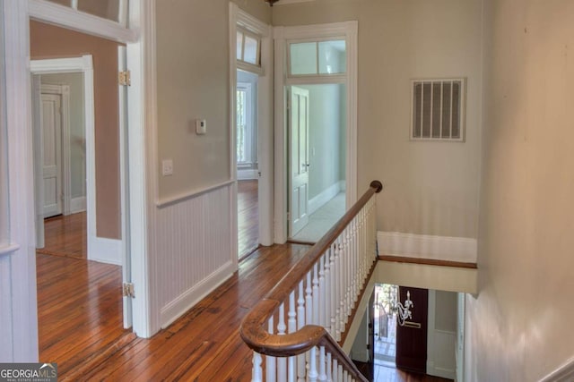 hall featuring baseboards, visible vents, an upstairs landing, and wood-type flooring