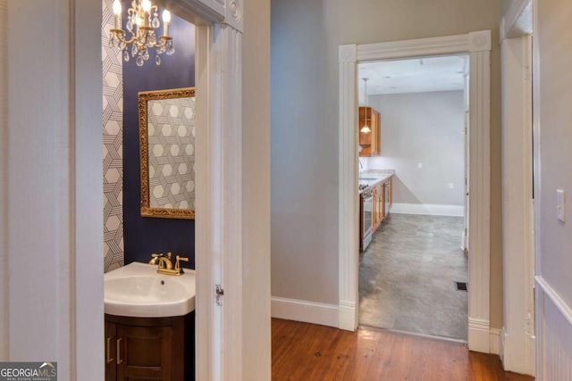 bathroom featuring a chandelier, wood finished floors, baseboards, and vanity