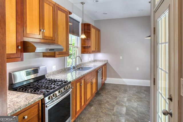 kitchen featuring stainless steel appliances, a sink, light stone counters, brown cabinetry, and under cabinet range hood