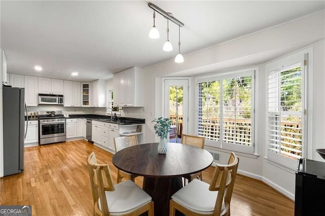 1420 Defoors Dr NW, Atlanta, GA 30318 - kitchen with white cabinets, light wood finished floors, stainless steel appliances, dark countertops, and pendant lighting