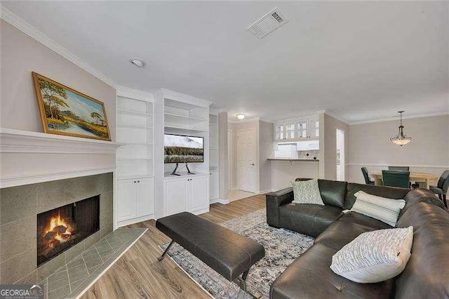 110 Barrington Hills Dr Unit 110, Atlanta, GA 30350 - living room featuring crown molding, wood finished floors, built in features, a tile fireplace, and visible vents