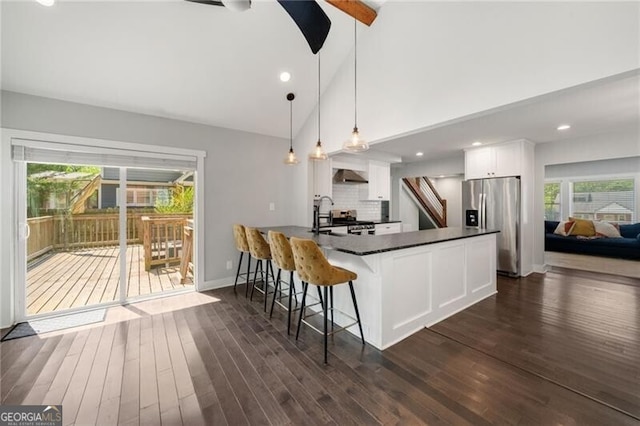 1535 Deerwood Dr, Decatur, GA 30030 - kitchen featuring wall chimney exhaust hood, stainless steel appliances, dark countertops, a kitchen bar, and white cabinetry
