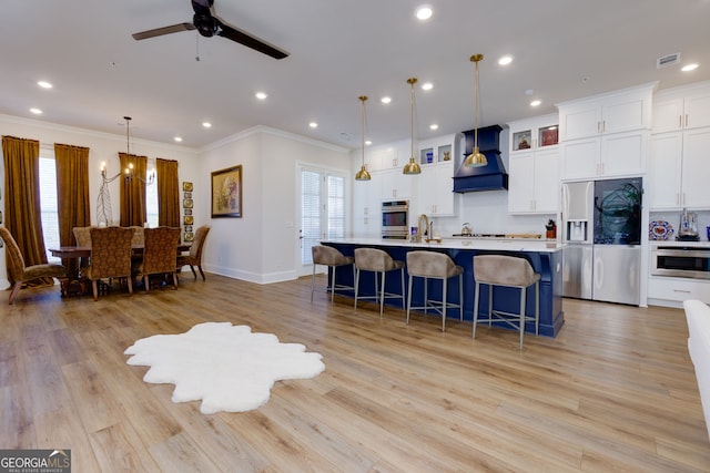 kitchen with custom range hood, stainless steel fridge with ice dispenser, ornamental molding, a kitchen bar, and a sink