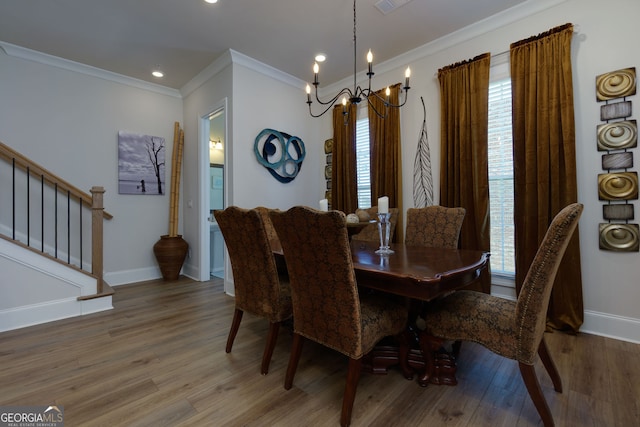 dining room featuring a chandelier, ornamental molding, wood finished floors, baseboards, and stairs