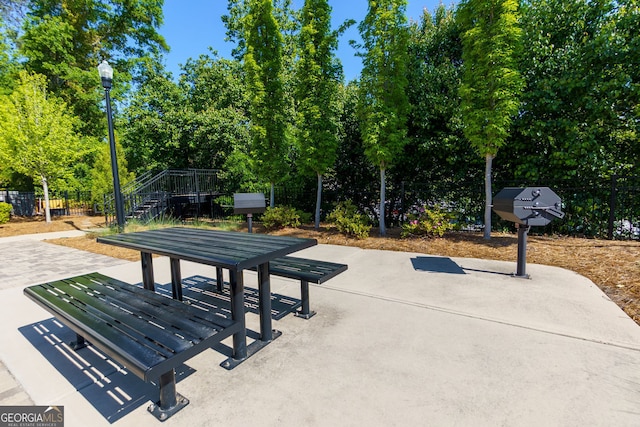 view of home's community with fence, stairs, a patio, and view of wooded area