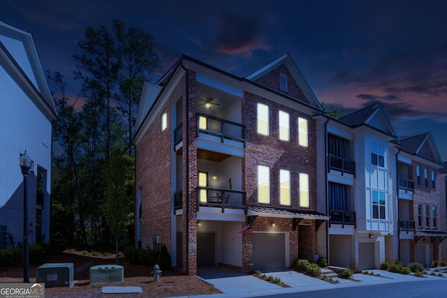 view of front of home with a balcony, a garage, brick siding, concrete driveway, and central air condition unit