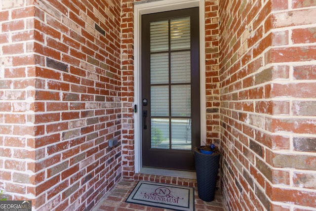 view of exterior entry featuring brick siding