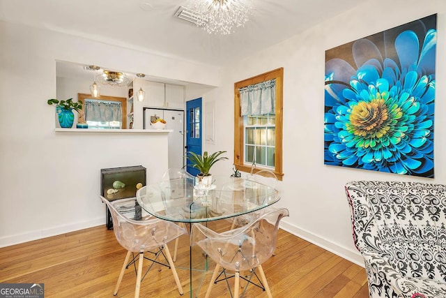 dining area with wood finished floors, visible vents, baseboards, and a notable chandelier