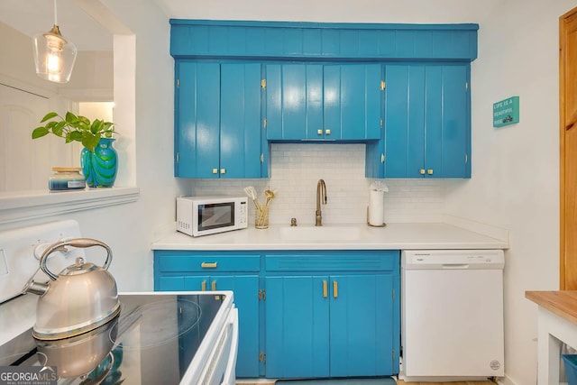kitchen featuring light countertops, decorative backsplash, a sink, and white appliances