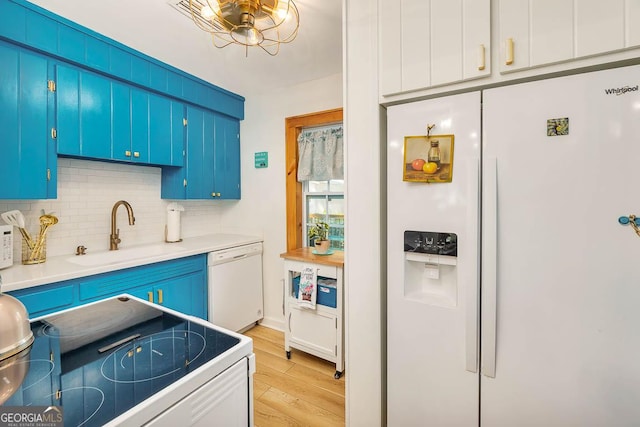 kitchen featuring decorative backsplash, light wood-style flooring, white appliances, and a sink