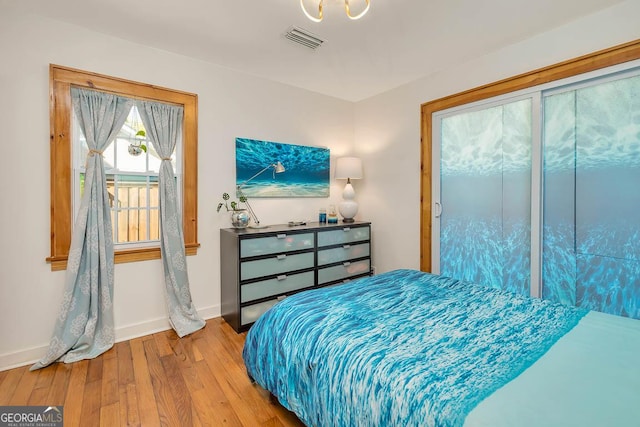 bedroom with wood finished floors, visible vents, and baseboards