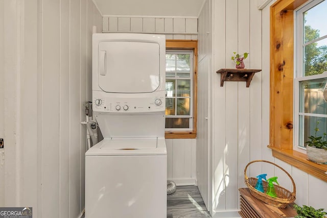 clothes washing area with stacked washer and clothes dryer, a decorative wall, and laundry area