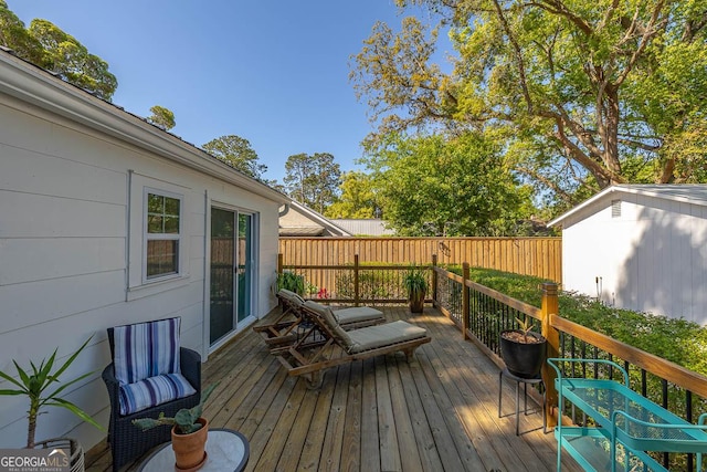 deck featuring an outdoor structure, fence, and a storage unit