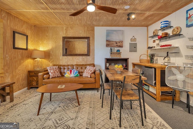 interior space with wood walls, electric panel, wood ceiling, ceiling fan, and baseboards