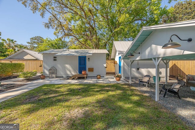 rear view of property featuring a lawn, a patio, a fenced backyard, and metal roof